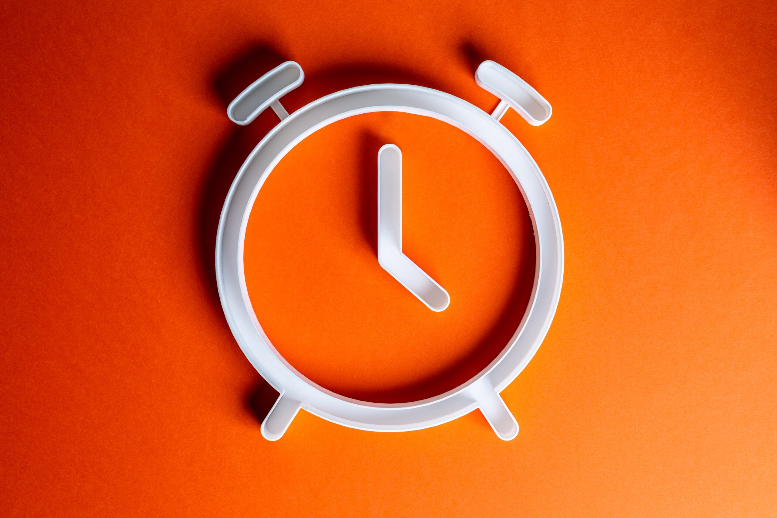 White alarm clock icon on an orange background